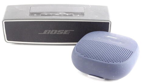 A Bose Soundlink Mini, 18cm wide, with wire and other accessories.