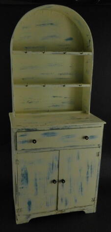 A miniature child's Dutch style dresser, with arched plate rack, frieze drawer and two cupboard doors on bracket feet, 33cm high.