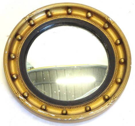 A gilt gesso circular convex wall mirror, with ebonised reeded slip, 42.5cm diameter.