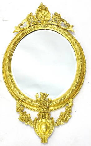 A late 19thC gilt gesso oval wall mirror, the elaborate frame decorated with flowers, grapes, leaves, cartouches, etc. (AF), 78cm x 43cm.