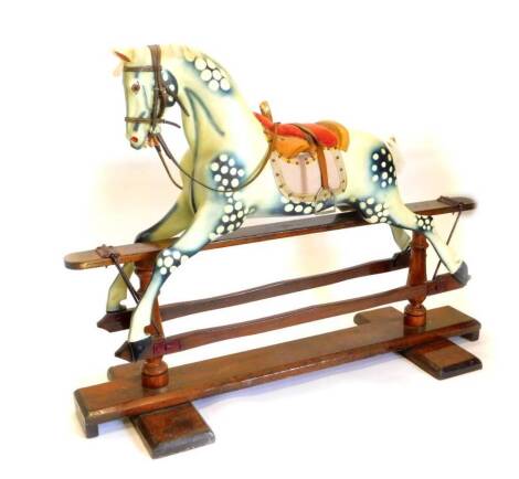 An Ayres type rocking horse, the dapple grey painted horse with velvet and leather padded saddle, on a trestle type base, the hinged painted in deep red, with turned supports and H shaped base, 171cm wide overall.