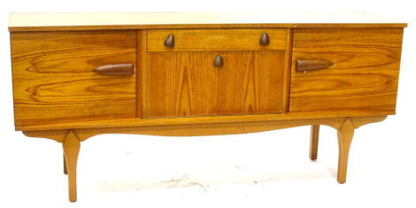 A 1960s/1970s teak concave shaped sideboard, with single frieze drawer above a fall front door flanked by two further doors each with bullet shaped handles on part turned legs, 75cm high, 167 wide.