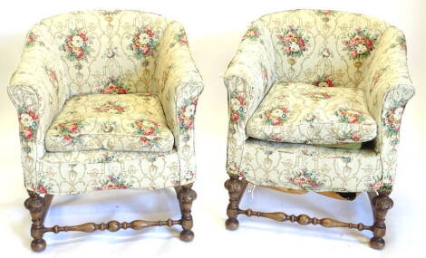 A pair of walnut tub shaped armchairs, upholstered in floral fabric, on part turned carved legs with turned stretcher.