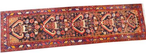 A modern Persian runner, with a central pole medallion, on a navy ground, decorated with flowers, geometric devices etc., three wide borders, 400cm x 110cm.