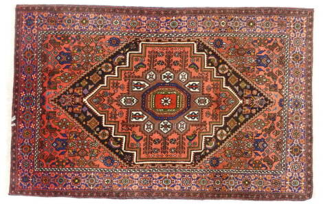 A Persian rug, with a central red and black lozenge design, red spandrels, one wide and one narrow border, 128cm x 81cm.