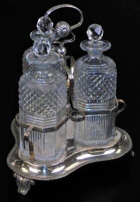 An Edwardian silver plated and cut glass three bottle tantalus, with compressed ring handle, set with a gadrooned flower head design, on scroll supports, raised above three bottles each partially hobnail cut with a repeat diamond pattern on a clover leaf - 3