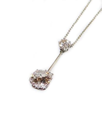 A two diamond drop pendant, the top diamond, round old cut, of 5.2mm (0.4ct) diameter, joined by a bar to the lower diamond, cushion cut, of 8.4mm x 8.4mm (2.25ct approx), set in white metal, suspended on a fine white metal chain