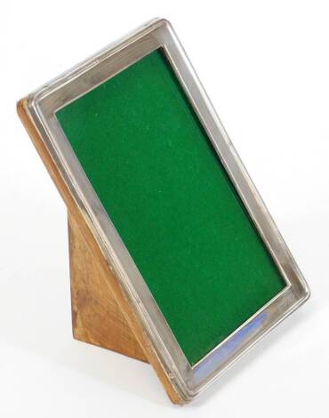 A George VI silver photograph frame, by Walker and Hall, of rounded rectangular outline with baize lined part oak easel back, Birmingham 1946, 21cm high, 14cm wide.