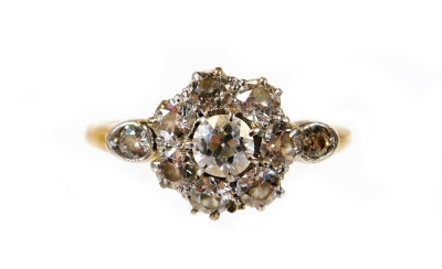 A Victorian diamond daisy ring, set with eight round brilliant cut diamonds to centre, central stone approx 0.20cts, surrounded by seven stones each approx 0.07cts, with tiny diamond set in platinum to each shoulder, yellow metal, stamped 18ct, ring size