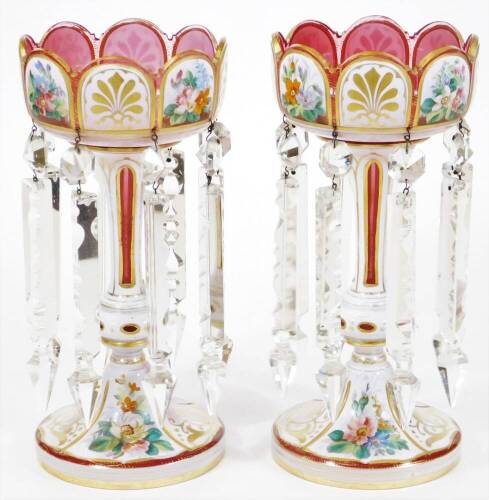 A pair of Victorian Bohemian pink and white overlay glass lustre vases, floral painted and having prismatic drops, 29cm high.