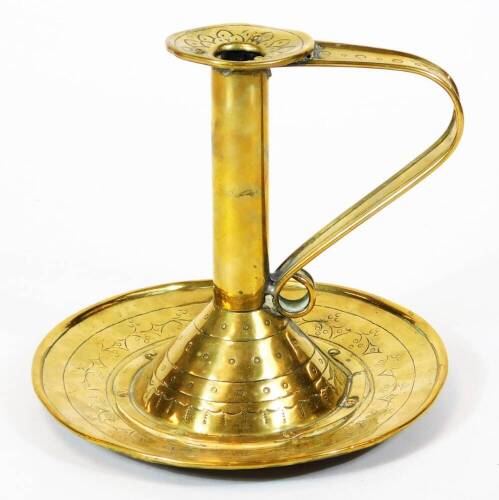 An 18thC brass candlestick, with cylindrical stem, shaped handle and circular plate base, decorated with a repeat leaf and berries pattern, 18cm high.