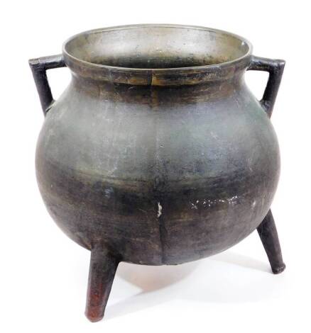 An 18thC bronze tripod cauldron, of globular form with angular handles, on three taper legs, 34cm high, 35cm wide.