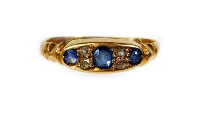 A Victorian 18ct gold sapphire and diamond dress ring, set with three pale blue sapphires and two diamonds, with ribbed and V shoulders, ring size K½, 2.1g all in.