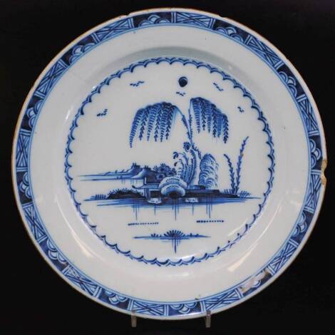 An 18thC tin glazed charger, decorated with an oriental garden scene in blue and white, 35cm diameter. (AF)