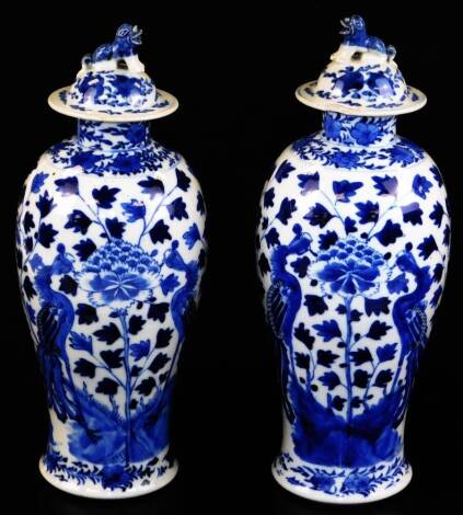 A pair of 19thC Chinese blue and white baluster vases and covers, each with dog of fo finial (1 AF), the bodies painted with ho-ho birds and peonies, four character Kangxi mark to base, 28cm high.