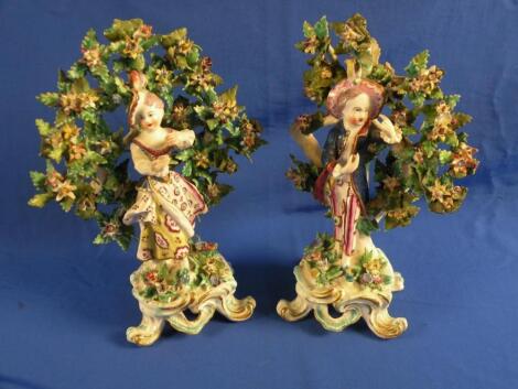 A pair of late 18thC Derby bocage figures of a gentleman wearing a blue