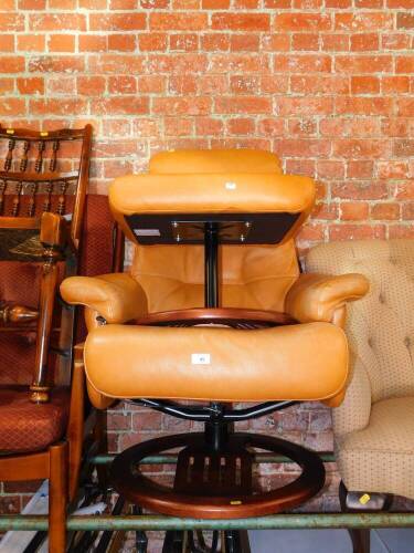 An orange leather swivel armchair, and matching stool.