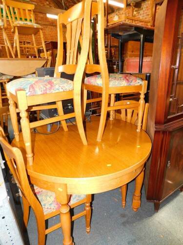 A light oak circular dining table, with one additional leaf, 116cm diameter, together with four single dining chairs.