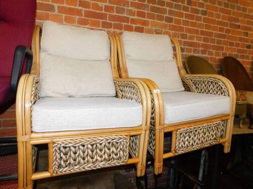 A pair of bamboo and cane conservatory armchairs, with loose cushion seats.