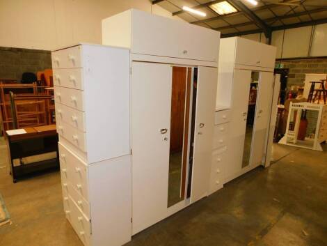 A pair of Albro white MDF double wardrobes, together with two five drawer chests, a pair of bedside chests, a further single chest, double headboard and a robing mirror. (9)