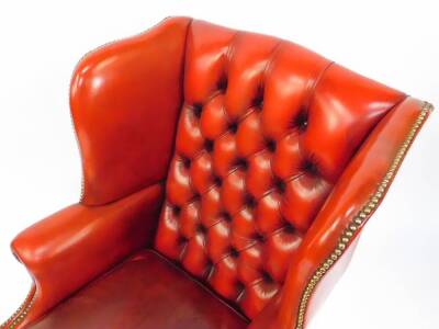 An oak framed red leather button back wing armchair, with loose cushion seat, and brass stud work, raised on fluted square legs, united by an H frame stretcher. - 2