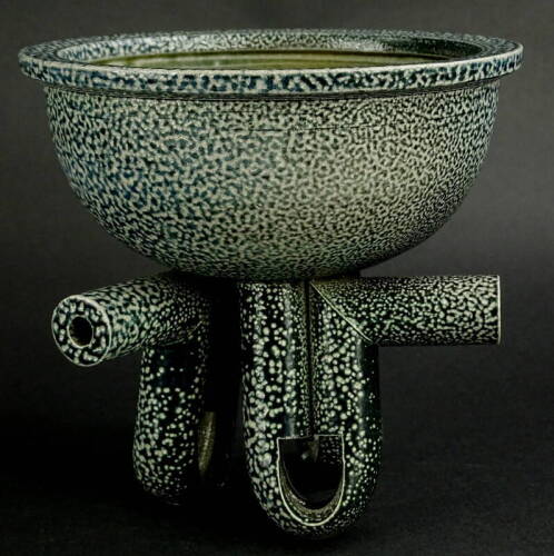 Walter Keeler (b. 1942). A studio stoneware tripod bowl, with all over speckled decoration, the legs of tubular shaped form, the side decorated with a single roundel, 16cm high, 17cm diameter. Provenance: The Dayabandhu Collection