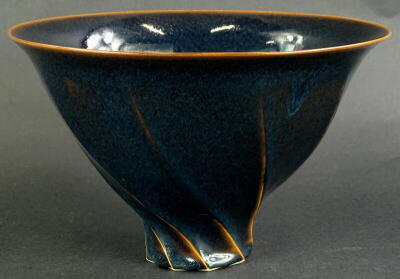 Chris Carter (b1945). A studio ceramic deep bowl, with wrythen shape, glazed in blue and mottled black glaze, circular mark to underside, 26cm diameter. Provenance: The Dayabandhu Collection