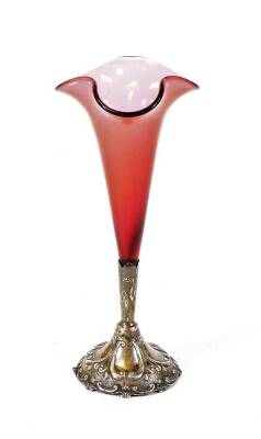 An Edwardian cranberry glass and silver epergne, with trumpet shaped section on a repousse decorated base, set with scrolls and beads, partially chased with further scrolls, Birmingham 1904, 23cm high, 1 ½ oz silver.