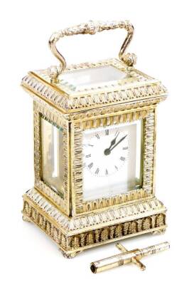 An Elizabeth II silver carriage clock, of small proportion, in elaborate five panel glass case with swing handle, on shaped feet with a lower acanthus leaf border and 3cm back plate with Roman numeric dial and keywind single train movement, marked Made In