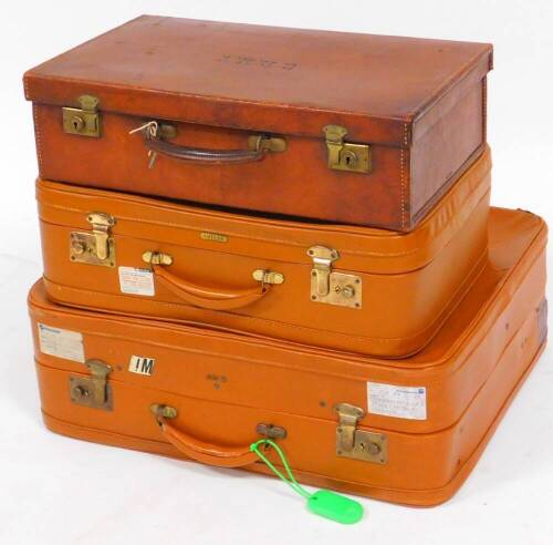 An early 20thC brown leather travel case, of rectangular form with shaped handle, initialled CRWV, with visible stitching, 14cm high, 51cm wide, 31cm deep and a graduated pair of vintage Antler suitcases in brown with metal locks. (3)