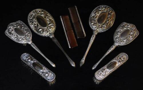 A silver plated dressing table set, to include two oval backed hand mirrors, 30cm high, clothes brush, hairbrush, comb, etc. each repousse decorated with scrolls and flowers. (a quantity)