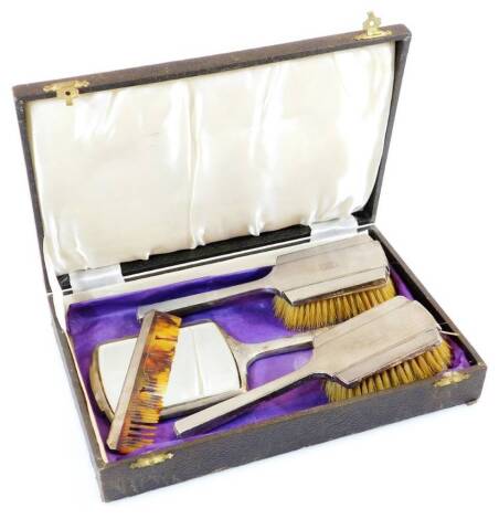 A George VI Art Deco silver dressing table set, comprising comb 16cm wide, hand mirror and two hairbrushes, Birmingham 1933, in fitted. (AF)