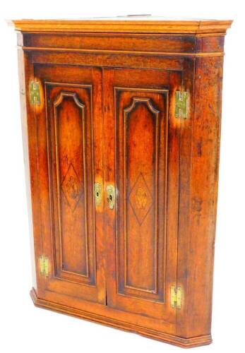 An 18thC oak hanging corner cupboard, with two panelled doors, with diamond inlay and heavy brass escutcheons, with a fitted interior, 104cm high, 79cm wide, 43cm deep.