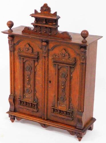 A late 19thC continental oak hanging cupboard, with raised carved panelled doors with a carved top, 59cm high, 44cm wide, 18cm deep. (AF)