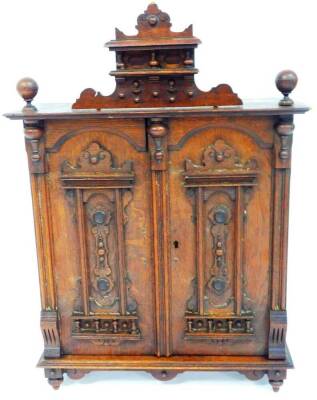 A late 19thC continental oak hanging cupboard, with raised carved panelled doors with a carved top, 59cm high, 44cm wide, 18cm deep. (AF) - 2