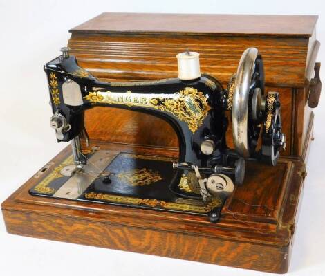 An early 20thC oak cased sewing machine, in shaped rectangular case with swing handles, 30cm high, 45cm wide, 24cm deep.