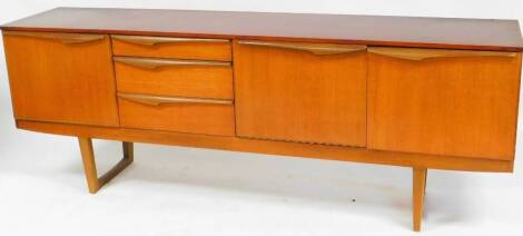 A vintage G Plan style teak sideboard, of shaped form with three graduated drawers and two fall openings on turned legs joined by front to back stretchers, unmarked, 74cm high, 198cm wide, 45cm deep. (AF)