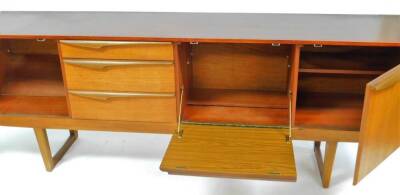 A vintage G Plan style teak sideboard, of shaped form with three graduated drawers and two fall openings on turned legs joined by front to back stretchers, unmarked, 74cm high, 198cm wide, 45cm deep. (AF) - 2