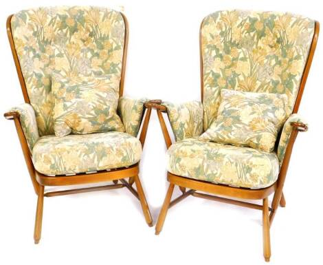 A pair of Ercol lounge chairs, each with floral cushions and turned legs joined by turned stretchers, 104cm high. (2)