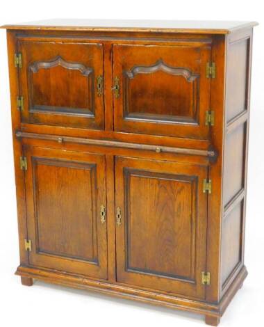 A 20thC oak cabinet, the rectangular top raised above a double cupboard with carved panels above further carved panels beneath on a rectangular moulded base terminating in compressed feet with three panel side, 112cm high, 91cm wide, 41cm deep.