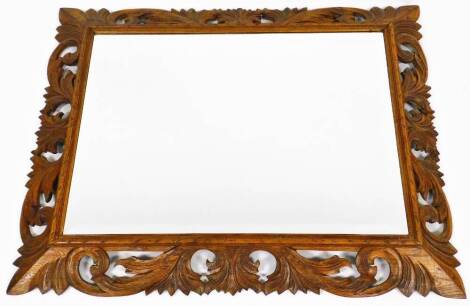 A 20thC oak mirror, with heavily carved scroll surround and bevelled glass, 110cm high, 88cm wide, 9cm deep.