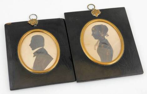 A matched pair of Victorian silhouettes, of a lady and gentleman each facing sinister, of oval form in ebonised frames, 9cm x 8cm. (2)