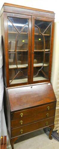 An early 20thC oak bureau bookcase, the upper section with astragal glazed doors revealing shelves, above a fall and three drawers beneath on cabriole legs with pad feet, 203cm high, 75cm wide, 45cm deep.