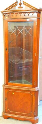 A mahogany finish corner display cabinet, with broken pedimented top and urn finial, 200cm high, 65cm wide.