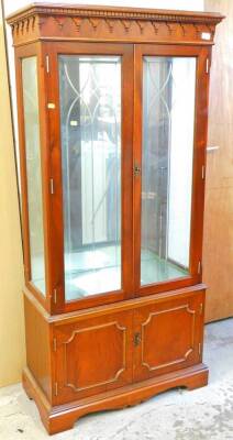 A mahogany finish display cabinet, with a moulded dentil cornice, raised above two glazed doors, above double panelled cupboards on bracket feet, 163cm high, 80cm wide, 37cm deep.