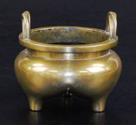 A Chinese bronze tripod censer, with bulbous body and twisted loop handles, six character Xuande seal mark to the base, probably 18thC, 9cm high, 10cm diameter.