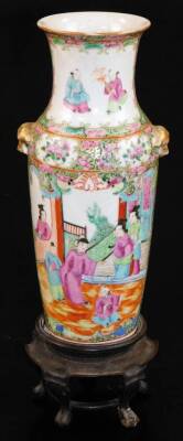 A Cantonese famille rose baluster vase, decorated with panels of court figures surrounded by flowers with further panels, predominately in pink, green, blue and orange, with gilt animal mask handles, 19thC, 25.5cm high, together with a hardwood stand. (2)