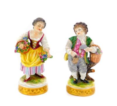 A pair of 20thC Volkstedt porcelain figures, of a boy with grapes and a girl with flowers, raised on circular bases, 15cm high.