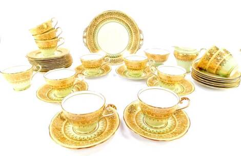 An Aynsley porcelain tea service, gilt decorated with mistletoe against a light green and peach ground, pattern C771/2, printed and painted marks, comprising a pair of bread plates, cream jug and sugar bowl, twelve tea cups, saucers and tea plates.