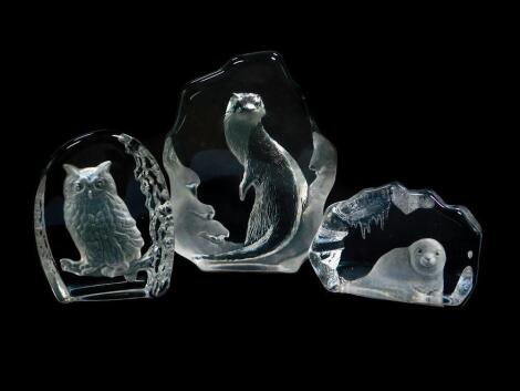 A Mats Jonasson intaglio glass sculpture carved as an otter, etched mark, 16cm high, another intaglio carved as a seal pup, 11.5cm wide, and an unattributed intaglio carved as an owl perched on a branch, 11.5cm high. (3)